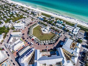 An aerial view of a coastal urban area with a central plaza, surrounding buildings, and a beach.
