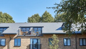 A multi-story residential building with brick facade, multiple balconies, and a clear sky. - Host & Stay | St Johns Mews (York)