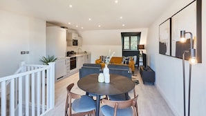 A modern interior with a dining area featuring a round table and chairs, a kitchen with white cabinets, and a living area with a sofa and a coffee table. - Host & Stay | St Johns Mews (York)