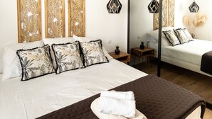 A hotel room with a large bed, a smaller bed, and a nightstand with a lamp.