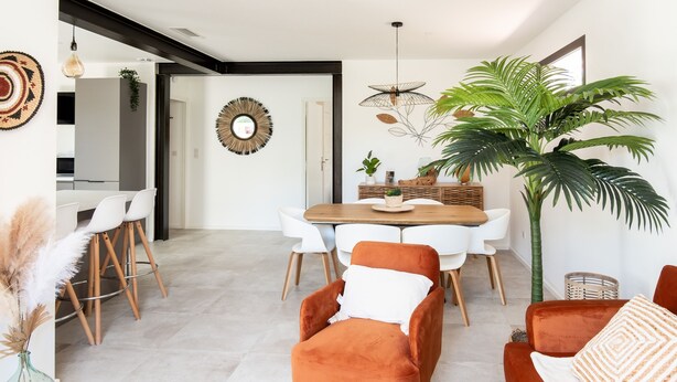 A modern living room with a wooden dining table, orange sofa, and white chairs.