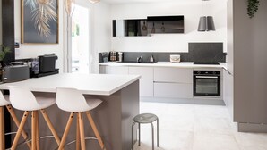 A modern kitchen with a central island, bar stools, and a built-in oven.