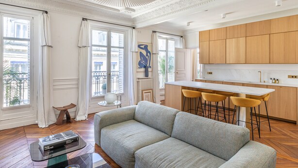 A modern living room with a sofa, a coffee table, and a dining area with chairs. - Appartement Haussmannien D'exception Coeur de Paris (Paris)