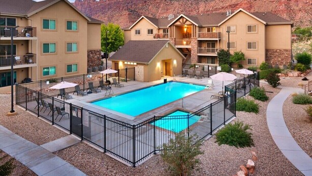 A hotel with a swimming pool, outdoor seating, and a view of red rock formations.