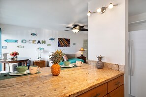 A kitchen with a wooden countertop, a ceiling fan, and a wall with fish decorations and the word "OCEAN".