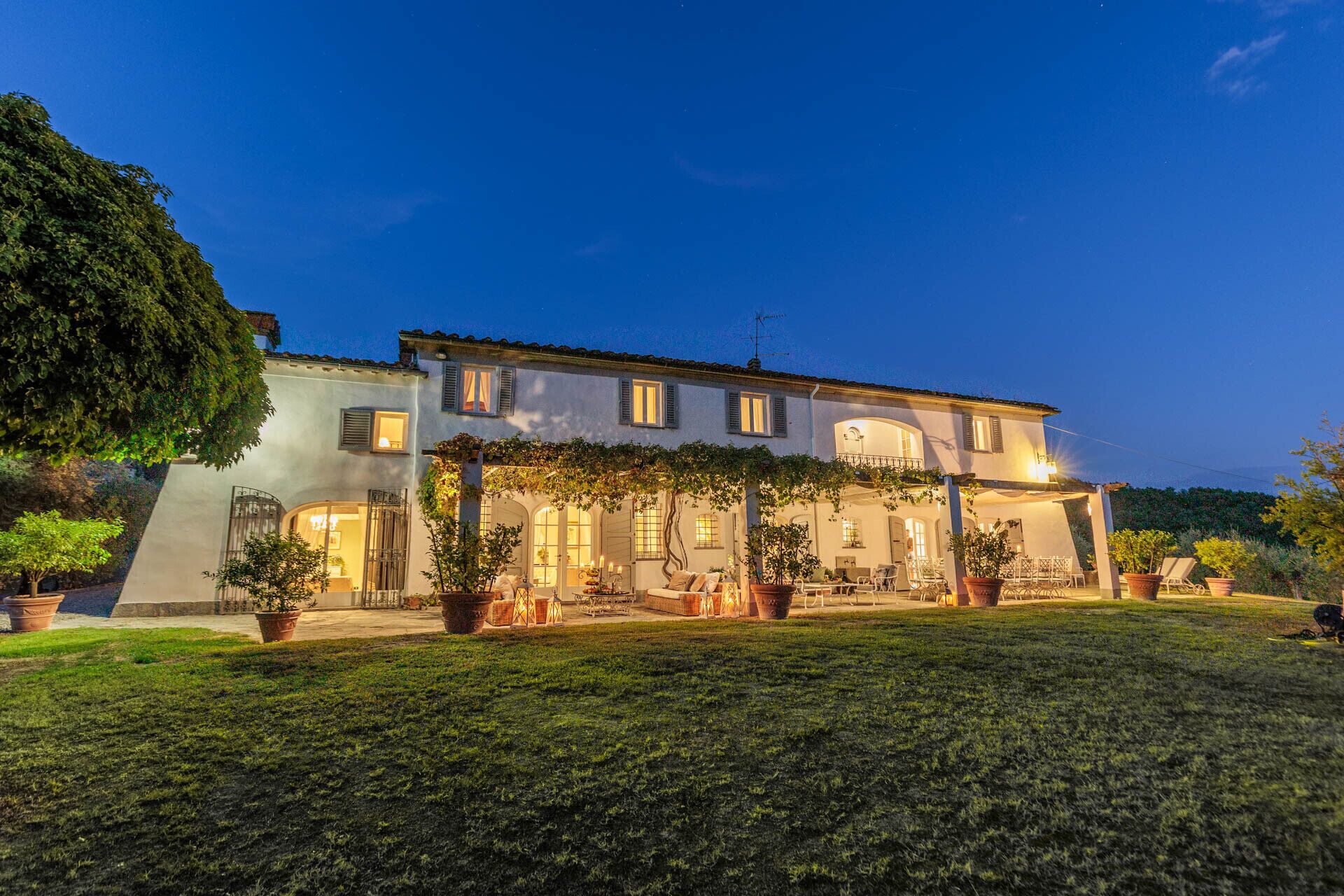A two-story building with a garden patio, potted plants, and outdoor seating.