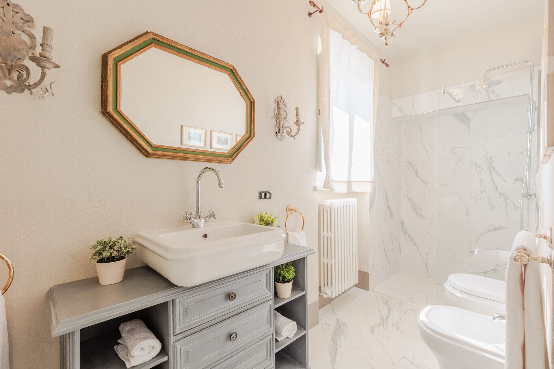 Ein Badezimmer mit weißem Waschbecken, Spiegel, Dusche und Handtuchwärmer.