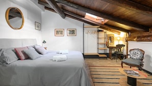 A bedroom with a bed, a chair, a round table, and a mirror.