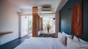 A modern hotel room with a large bed, a seating area with a vase of flowers, and a view of the outdoors. - Allia Residence Nusa Dua (Nusa Dua)