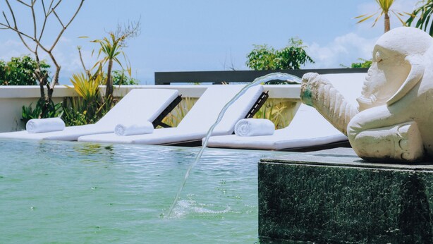 A pool area with lounge chairs and a statue. - Allia Residence Nusa Dua (Nusa Dua)