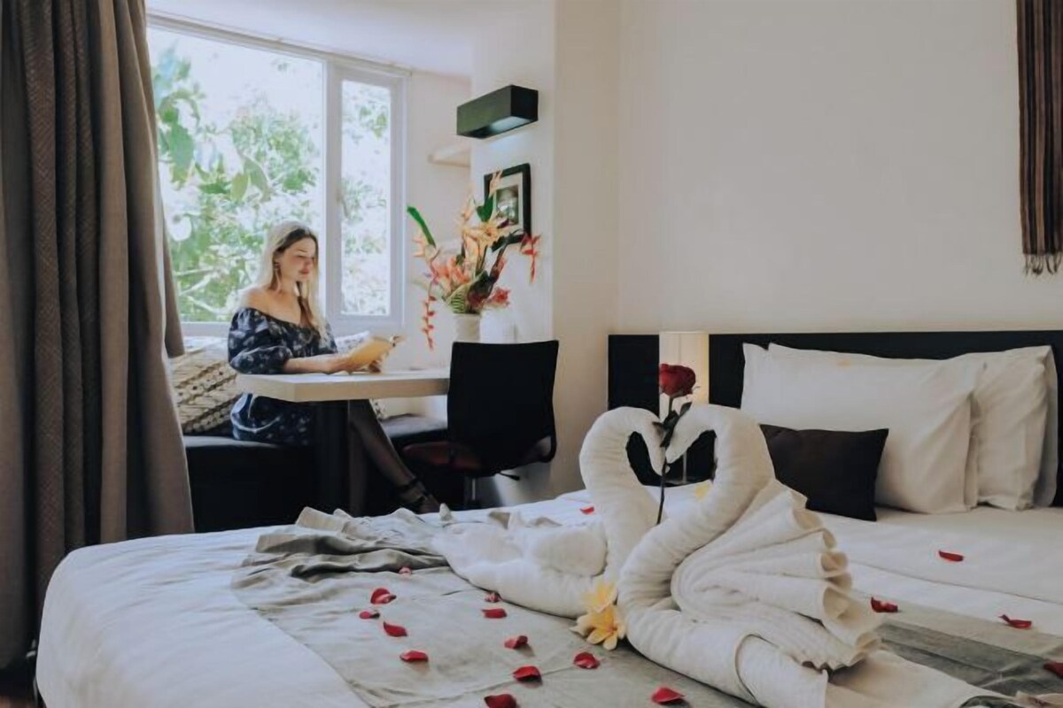 A hotel room with a bed, a desk, and a window.