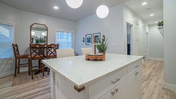 Una cocina moderna con encimera de mármol, sillas de madera e iluminación colgante.