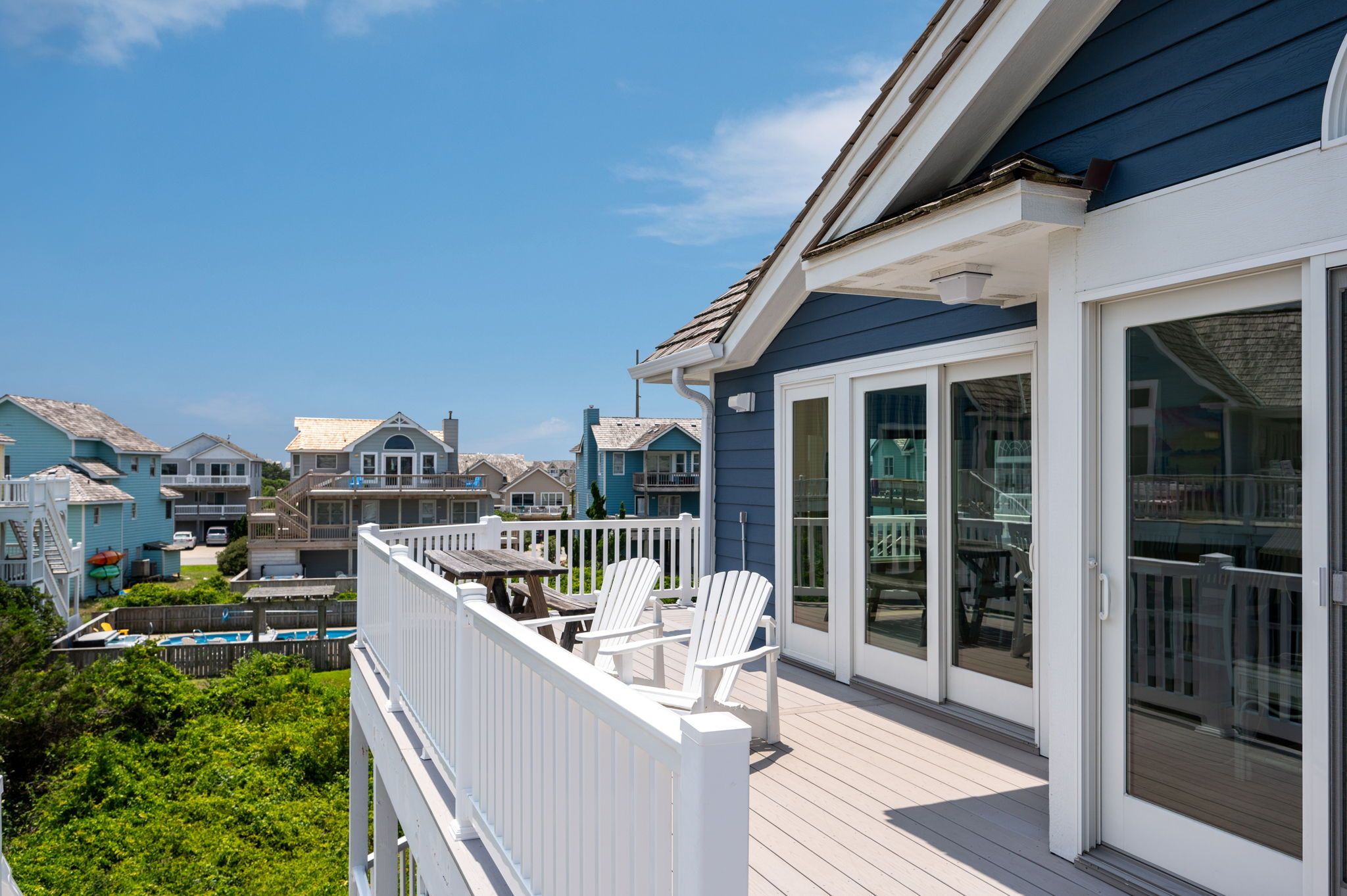 A residential property with a deck, outdoor seating, and a view of neighboring houses.