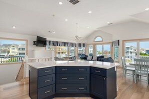 A modern kitchen with a large island, built-in appliances, and a view of the ocean.