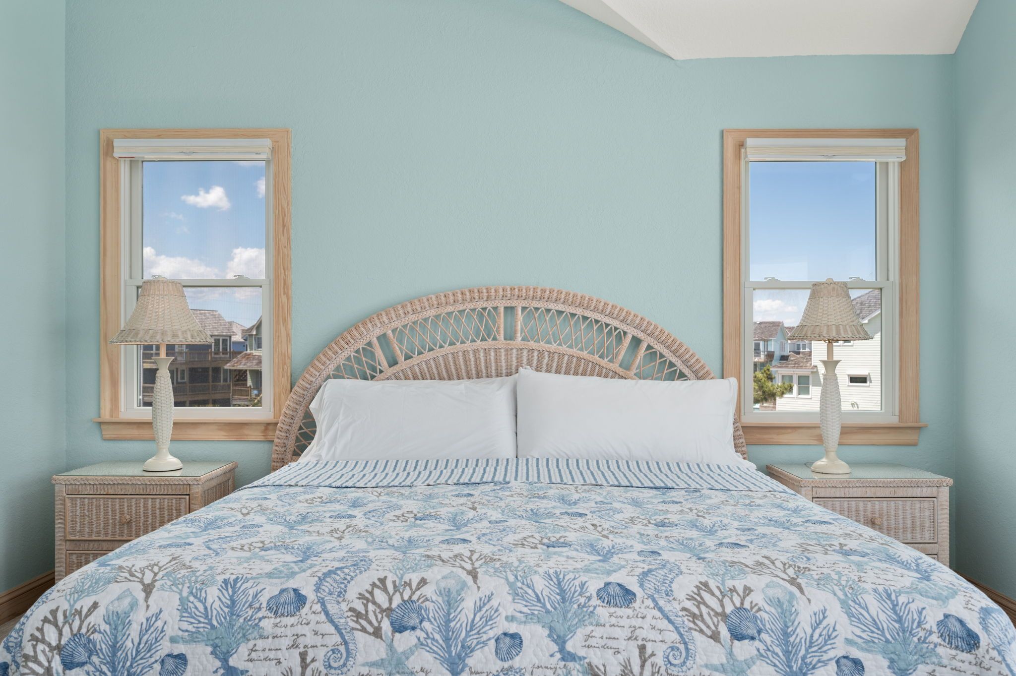 A bed with a woven headboard, two bedside lamps, and a patterned bedspread.