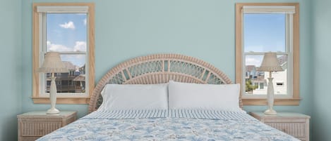 Una cama con cabecera trenzada, dos lámparas de noche y una colcha estampada.