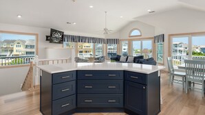 A spacious kitchen with a large island, dark cabinetry, and a ceiling fan. - C-Side: Semi-oceanfront, hot tub, community oceanfront pool, walkway to beach by house. (Nags Head)