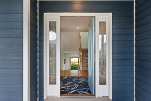 A doorway leading to a staircase with a blue door and a patterned rug. - C-Side: Semi-oceanfront, hot tub, community oceanfront pool, walkway to beach by house. (Nags Head)