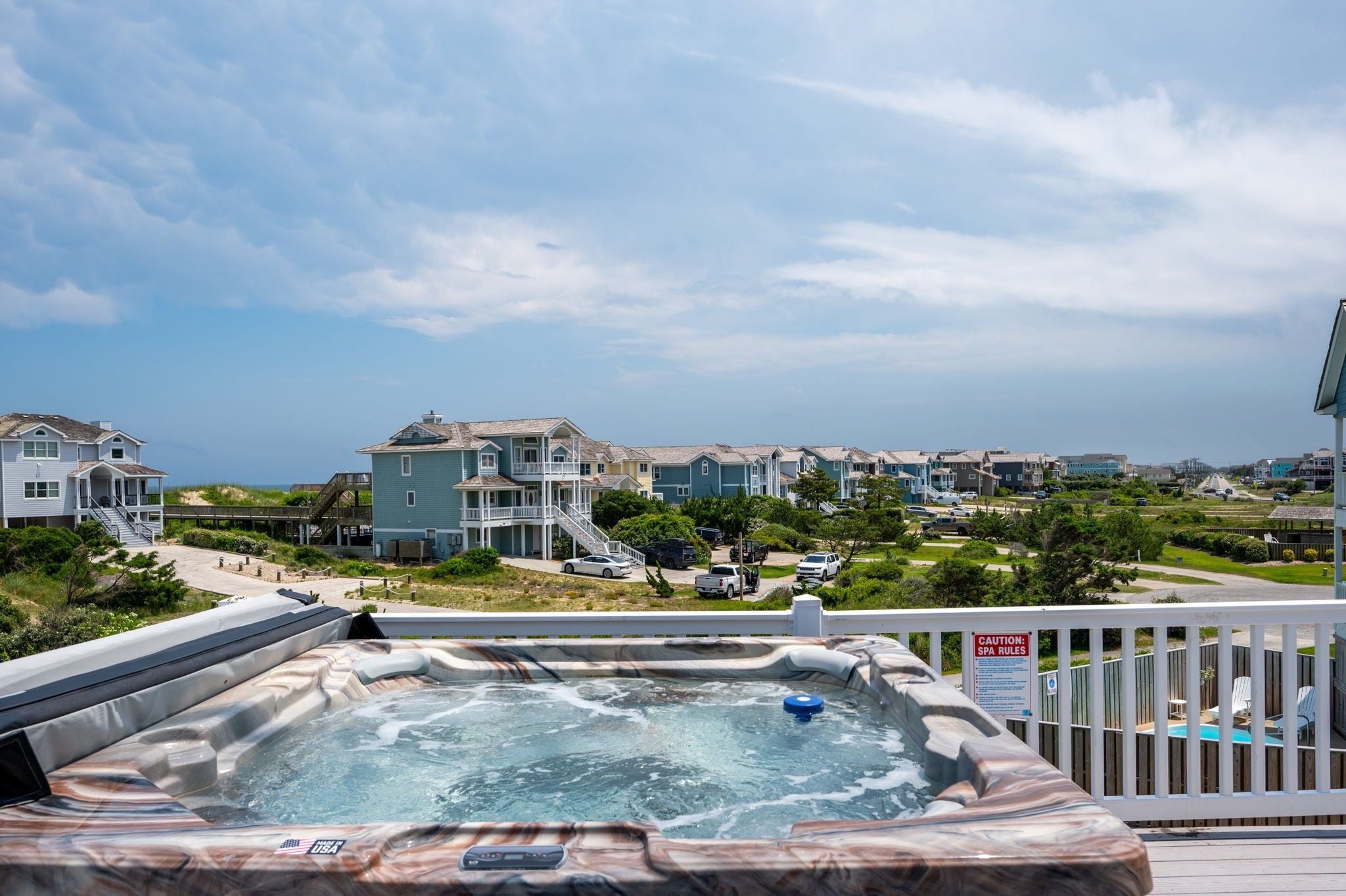 Ein Whirlpool auf einer Terrasse mit Blick auf eine Wohngegend und Häuser.