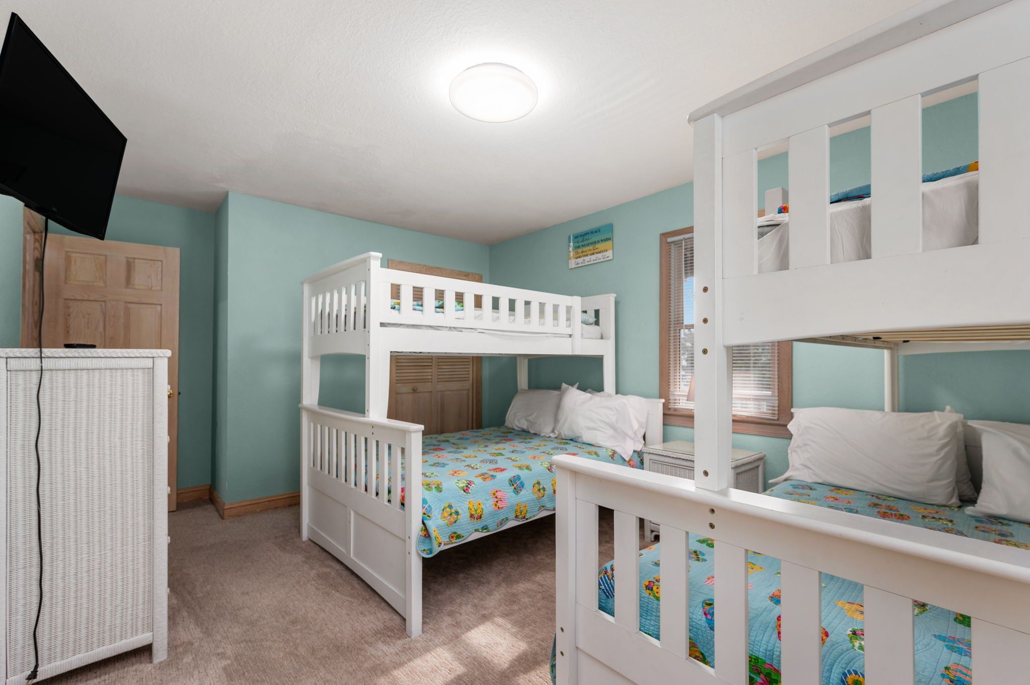 A children's room with bunk beds, a television, and a wardrobe.