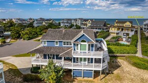 A coastal residential area with houses, a beach access path, and a view of the ocean. - C-Side: Semi-oceanfront, hot tub, community oceanfront pool, walkway to beach by house. (Nags Head)