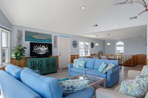 A spacious living room with a blue sofa set, a television, and decorative wall art.