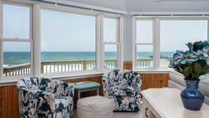 A room with large windows overlooking the ocean, wooden walls, and a white ceiling. - SeaAira: Oceanfront with unbeatable ocean views, renovated kitchen and baths (Nags Head)