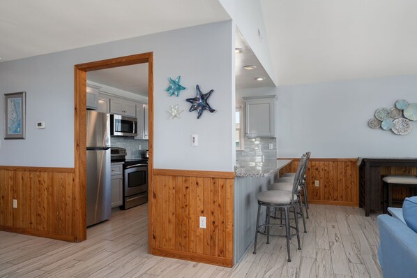 A modern kitchen with wooden paneling, stainless steel appliances, and decorative starfish wall art.