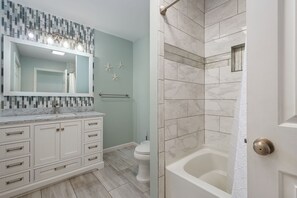 A bathroom with a white vanity, a large mirror, a shower with a glass door, and a toilet.