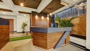 A reception desk with a wooden finish, a Dell computer, and a reception sign. - Worldtree Suites Manyata (Bengaluru)