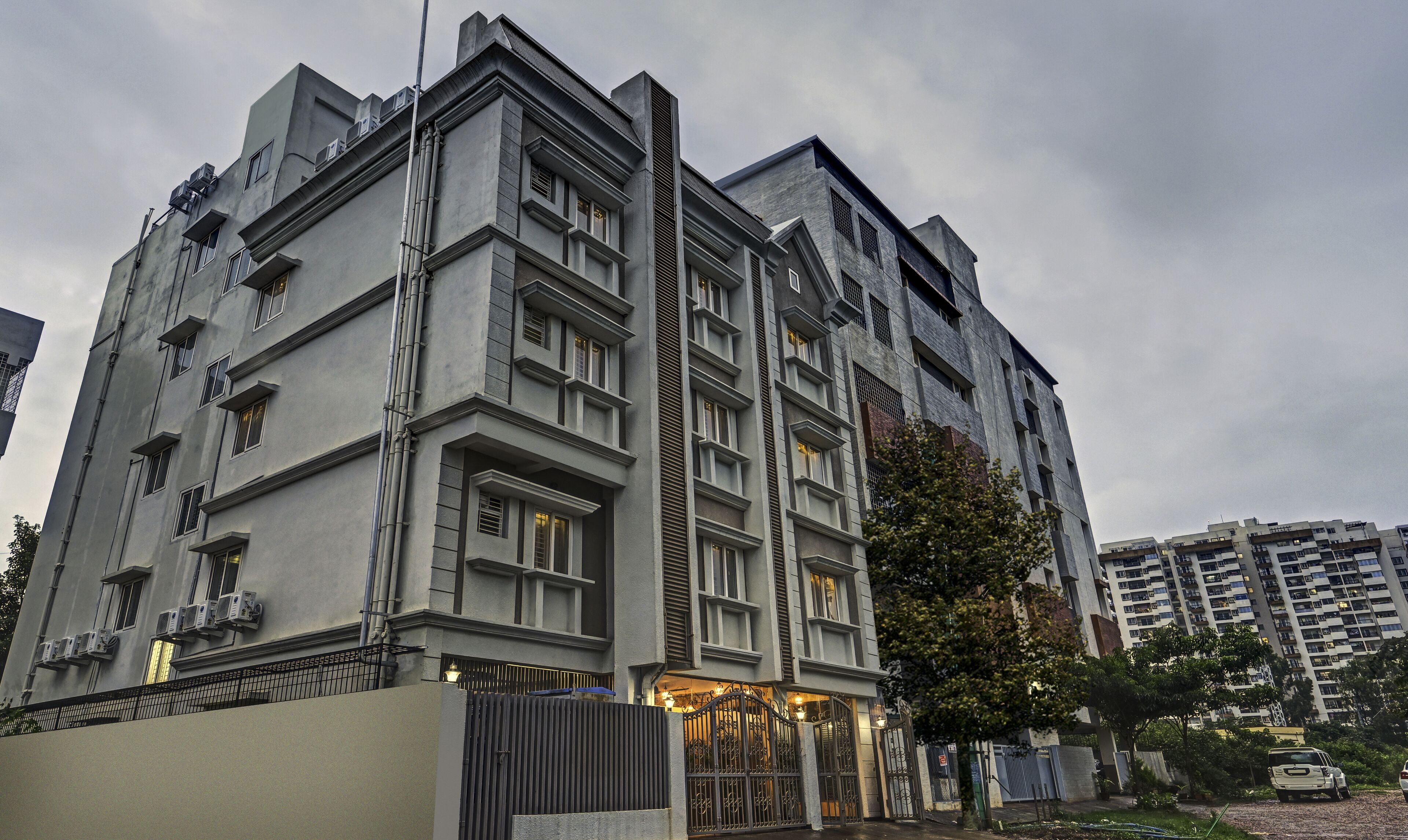 Un immeuble à plusieurs étages doté d’une architecture moderne, caractérisé par un élément vertical marquant et une entrée sécurisée par un portail.