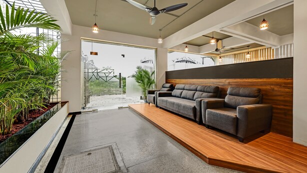 A modern reception area with a sofa, ceiling fan, and pendant lights. - Worldtree Suites Manyata (Bengaluru)