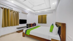 A modern hotel room with a bed, a TV, a desk, and a ceiling fan. - Worldtree Suites Manyata (Bengaluru)