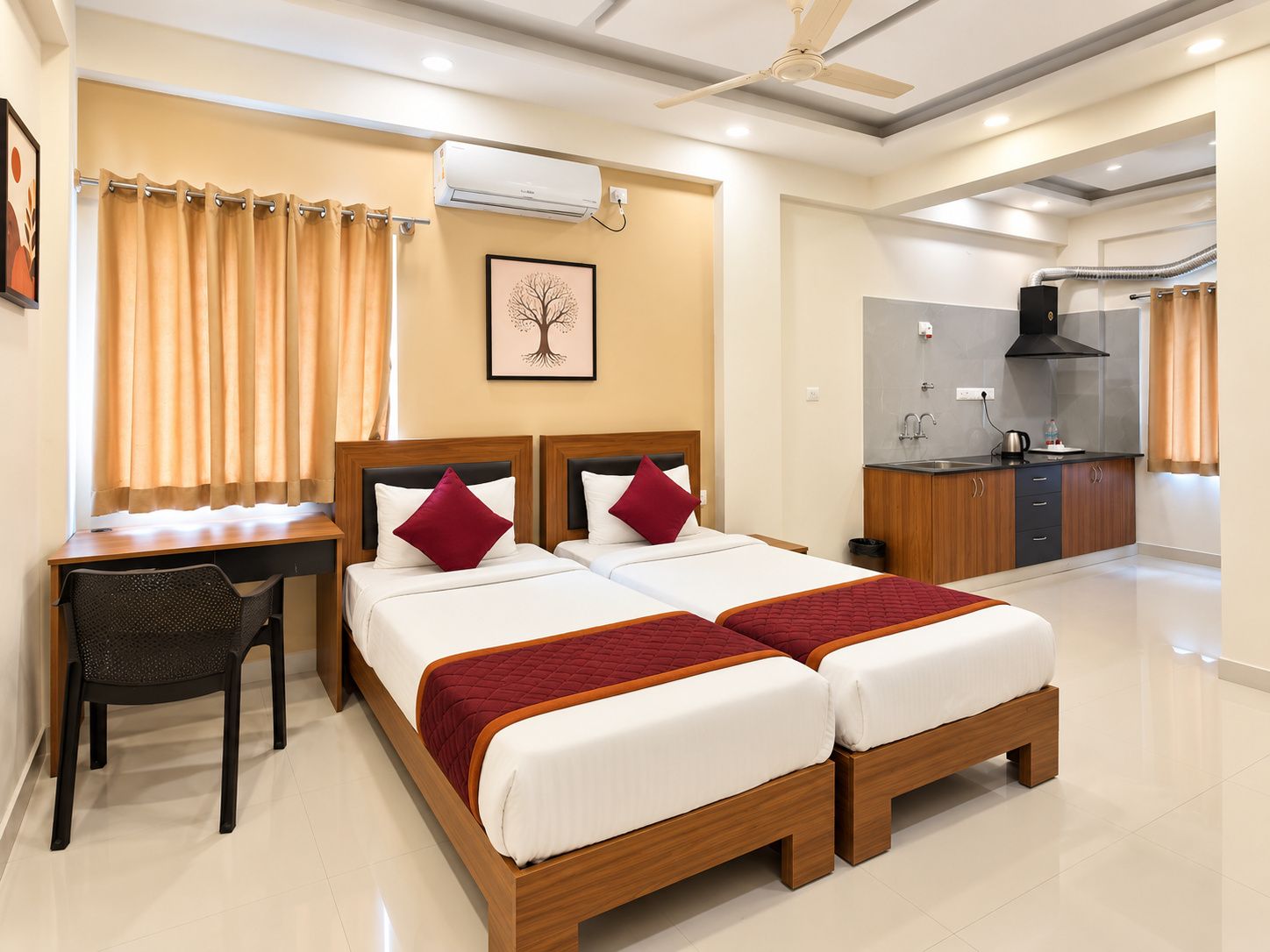 Habitación de hotel con cama doble, escritorio con silla, kitchenette y ventilador de techo.