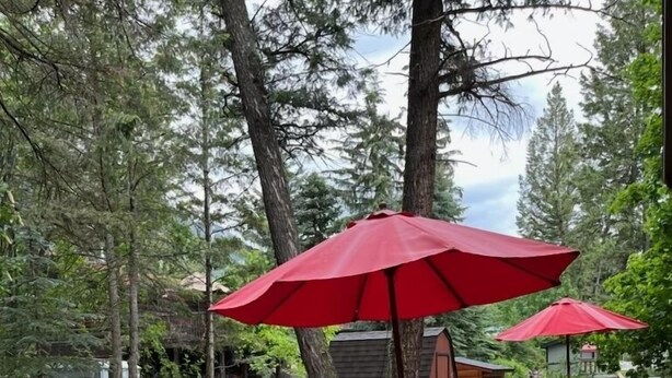 Een houten terras met tuinmeubilair en rode parasols.