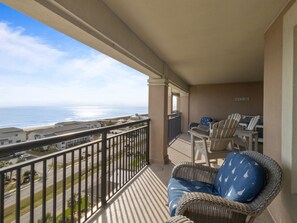 Un balcon agrémenté de meubles en osier, une vue sur l’océan et une pancarte indiquant « Beach Ave. ».