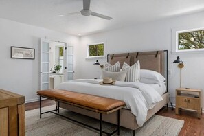 A bedroom with a bed, bench, bedside table, and a window. - Fab-Fred House, Patio Oasis, Fireplace, In Town (Fredericksburg)