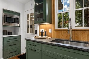 A kitchen with green cabinets, a stainless steel sink, and a microwave. - Fab-Fred House, Patio Oasis, Fireplace, In Town (Fredericksburg)