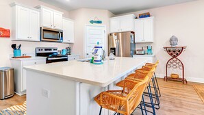 A modern kitchen with white cabinets, stainless steel appliances, and a central island with bar stools. - Bay View Retreat | Heated Pool | Dog Friendly | Near Beaches (Port St Joe)