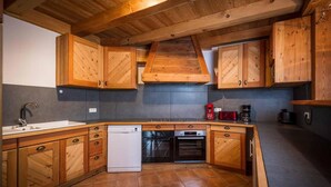 Eine Küche mit Holzschränken, einem Geschirrspüler, einem Backofen und einer Kaffeemaschine.