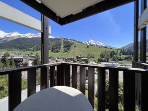 En balkon med udsigt over et bjerglandskab, inklusive sneklædte tinder og en landsby nedenfor.