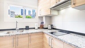 Une cuisine moderne dotée de plans de travail en granit, d’appareils électroménagers en acier inoxydable et d’armoires en bois.