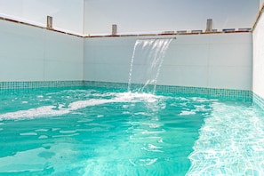 A swimming pool with clear blue water and a waterfall feature.