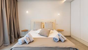 A modern hotel room with a large bed, two bedside tables, and a wardrobe.