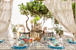 Une table dressée pour un repas, avec en arrière-plan la vue d’un arbre et d’un bâtiment.