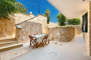 A stone-walled outdoor patio with a dining table set for four, surrounded by chairs. - A casa di Giulia e Sofia by BarbarHouse (Torre Suda)