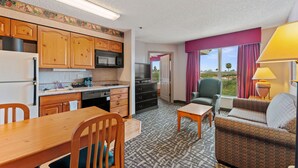 A compact hotel room with a kitchenette, a dining area, a sofa, and a view of the outdoors. - Metro Scottsdale Extended Stay (Paradise Valley)
