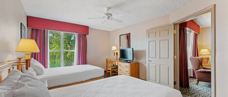 Ein Hotelzimmer mit zwei Betten, einem Fernseher, einem Schreibtisch und einem Sessel.