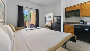 A bedroom with a bed, a desk, and a view of the outdoors. - Metro Scottsdale Extended Stay (Paradise Valley)