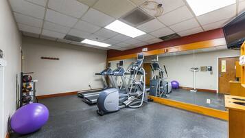 Une salle de sport équipée de tapis de course, de vélos elliptiques et de ballons d’exercice.